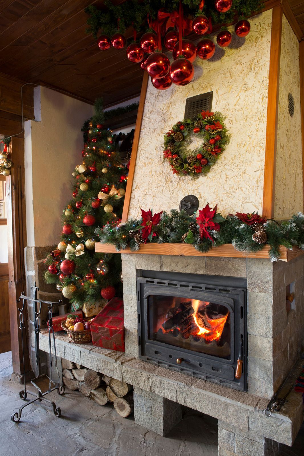 Cozy Christmas hearth with lit fireplace, decorated tree, wreath, and red ornaments