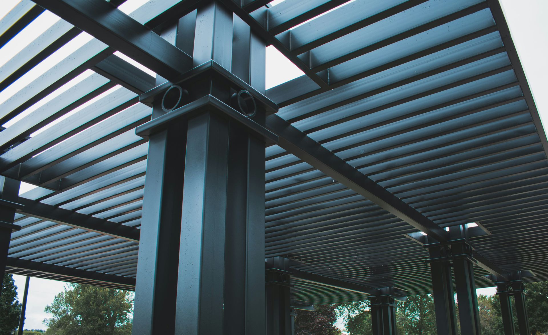 Modern metal pergola with curved beams and slatted roof in an outdoor garden