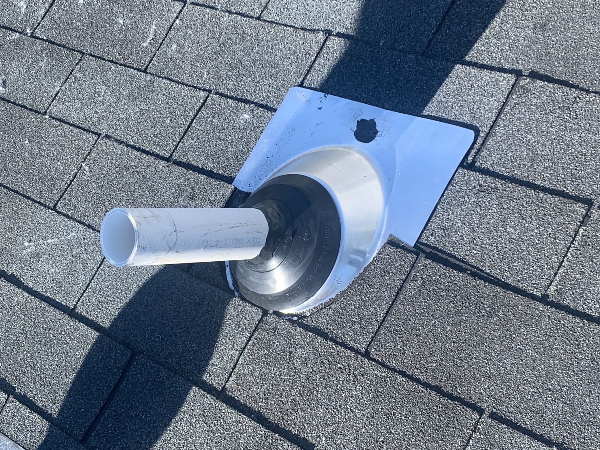 A white pipe is sitting on top of a brick roof.