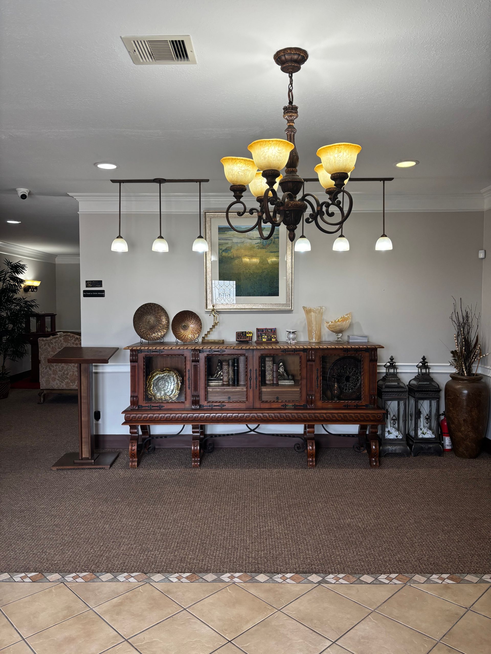 Elegant lobby with chandelier, wooden console table, carpeted floor, and decorative accents