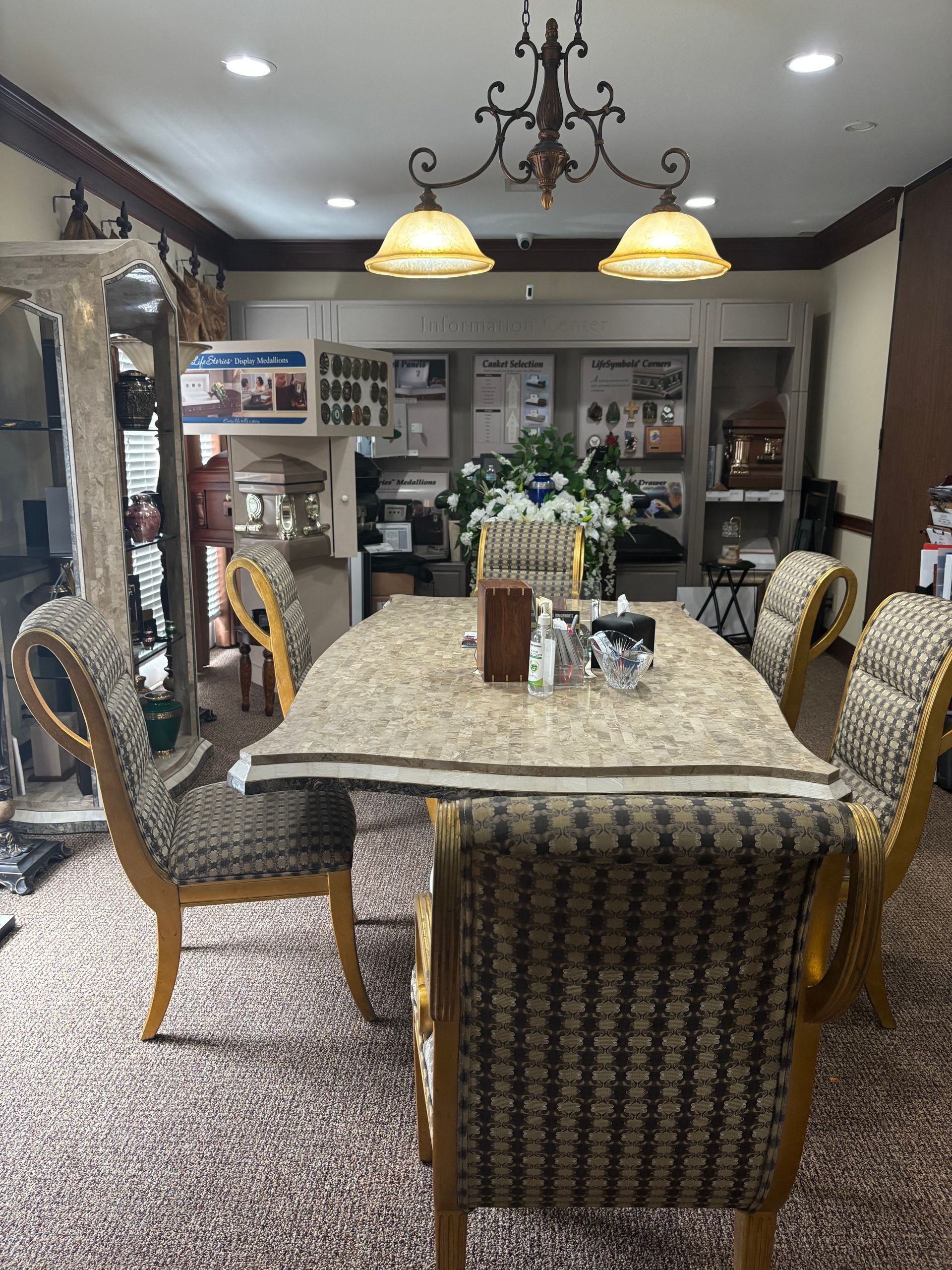 Elegant dining room with a marble table, patterned chairs, hanging lamps, and a chandelier.