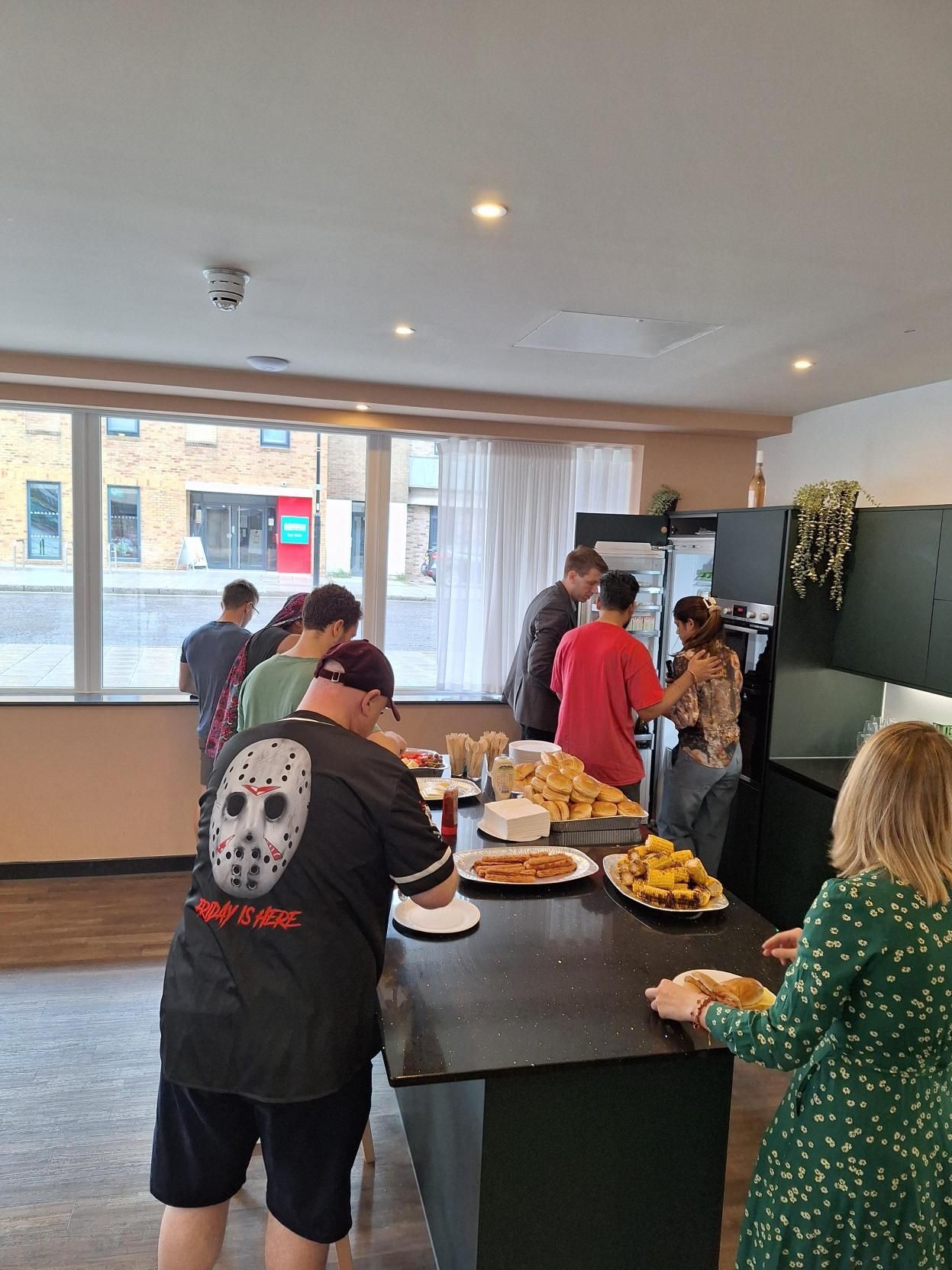 People gathered around a kitchen island with plates of food in a bright modern room.