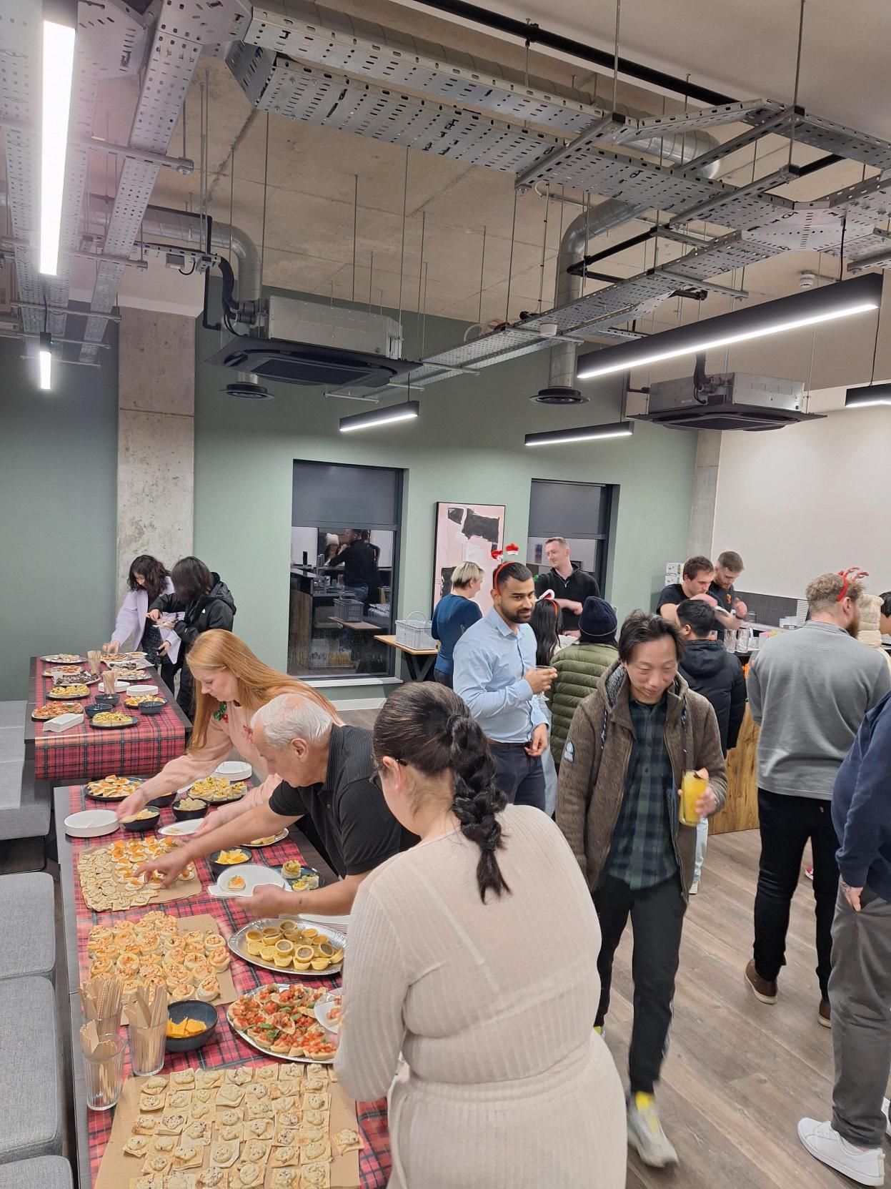 Buffet table in an office event space with people serving themselves and mingling around the room