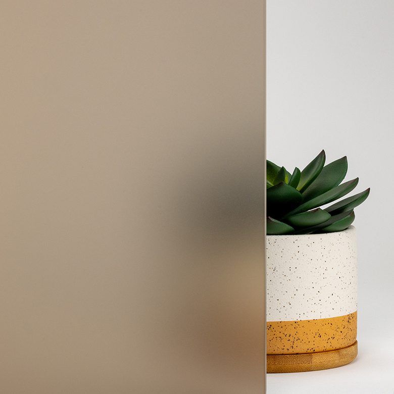 Frosted brown glass with a potted succulent plant on a white background.