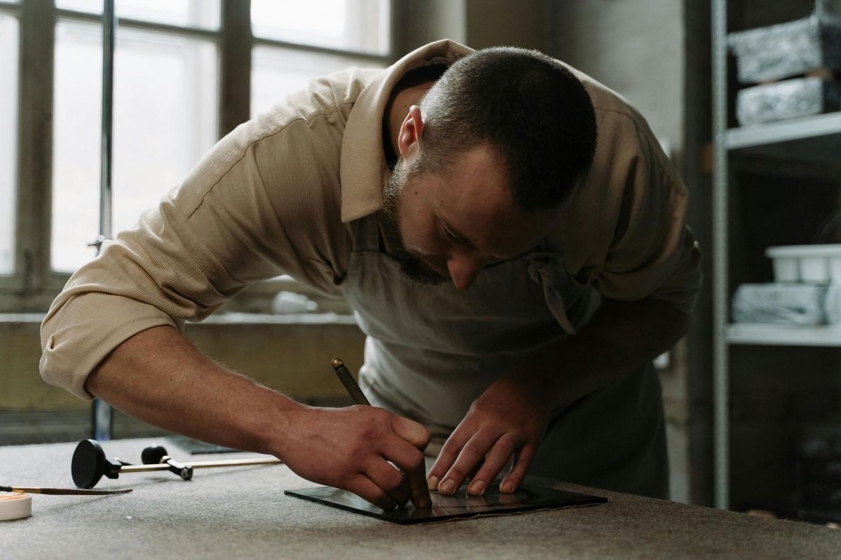A person carefully scoring glass on a workbench in a workshop.