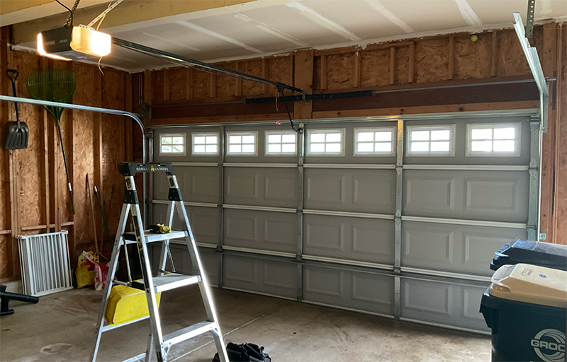 Garage interior with a ladder, work light, and closed gray overhead door