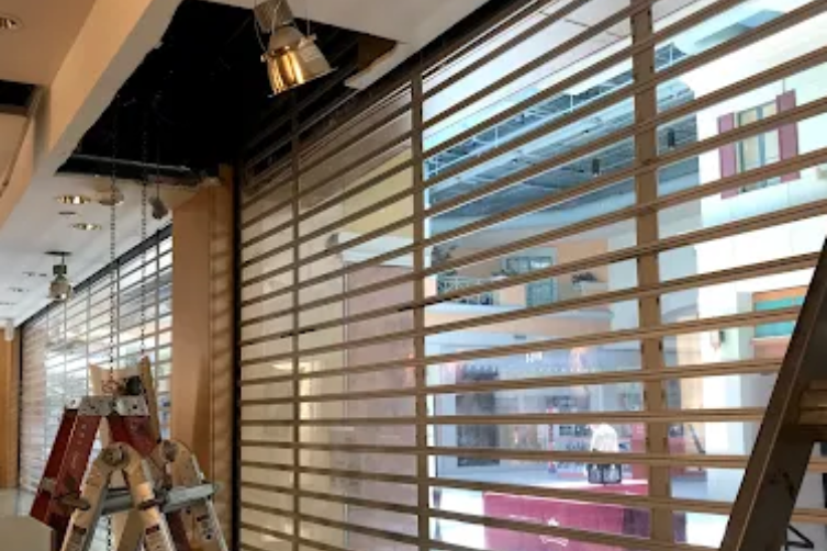 Interior under construction with ladders and horizontal window blinds along a bright wall