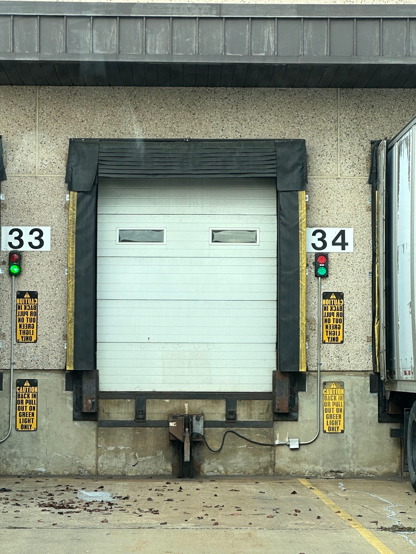 Industrial loading dock with a white roll-up door between bays 33 and 34
