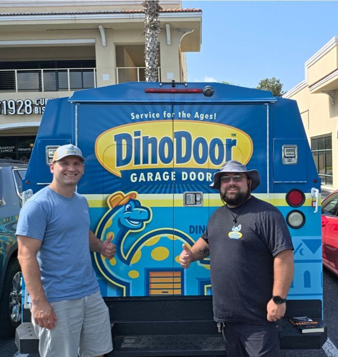 Two men standing in front of a blue DinoDoor garage door service van with dinosaur graphics.