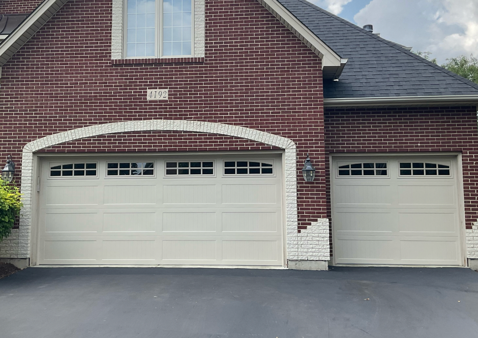 Brick house exterior with a two-car garage and a single-car garage, both with white doors.
