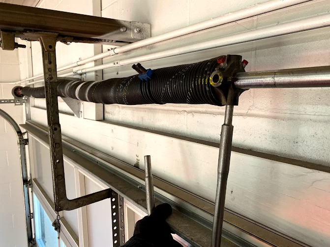 Insulated black pipe mounted on wall with metal brackets in a workshop or utility space