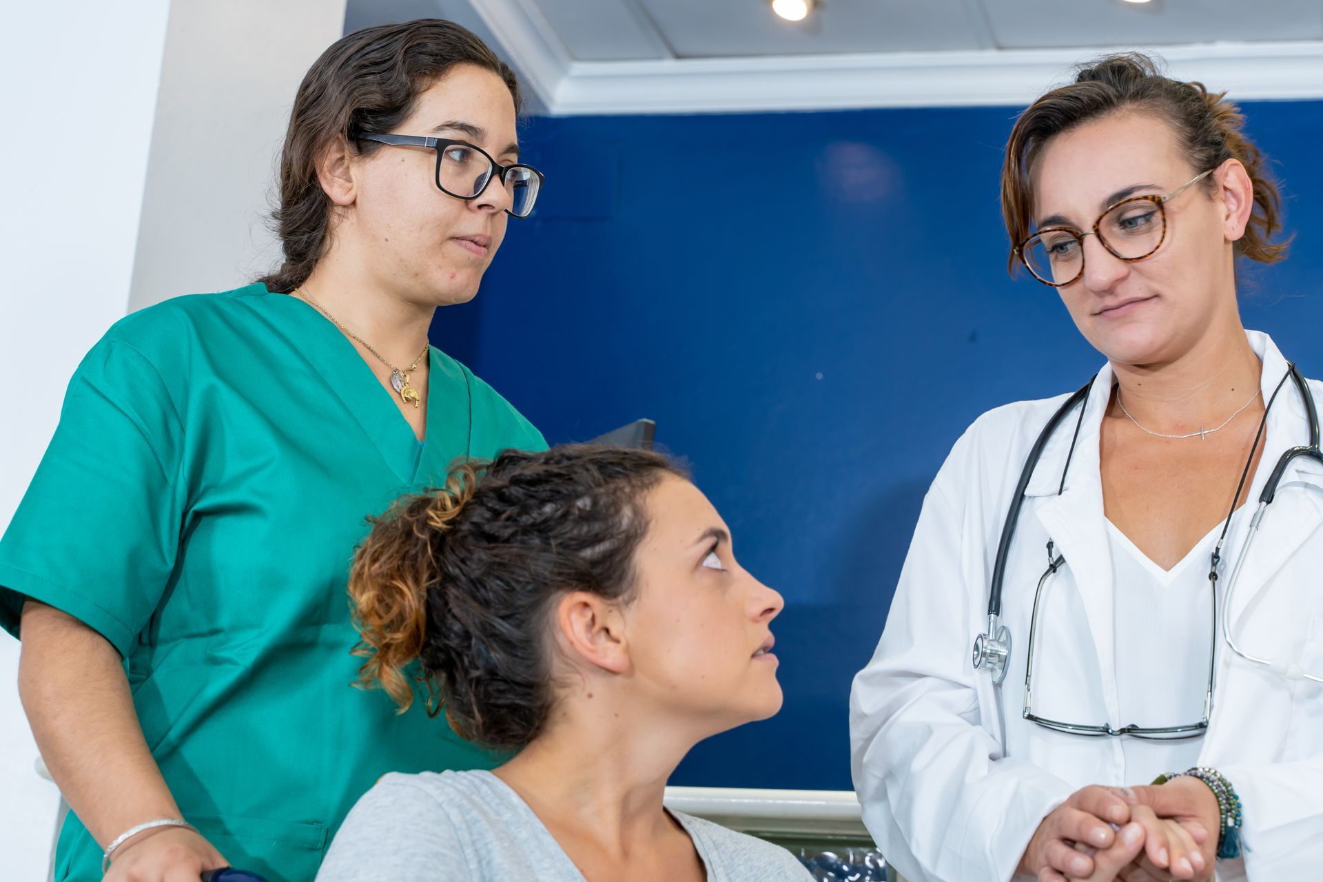 A doctor and two nurses are talking to a patient in a hospital.