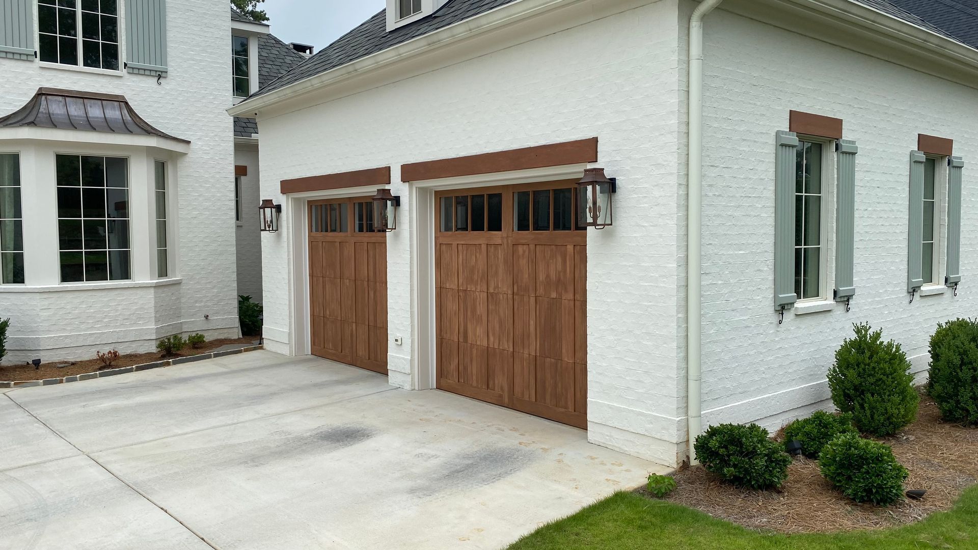 Two-car garage with brown doors, white brick exterior, brown trim, and concrete driveway.