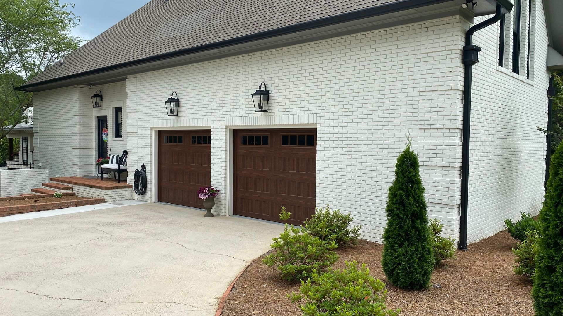 White brick house with brown garage doors and a concrete driveway.
