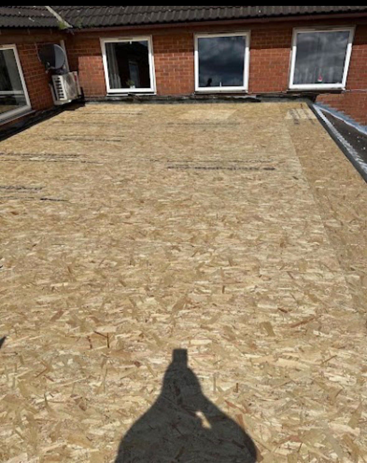 A residential roof under repair, featuring newly installed bright red waterproof membrane and horizontal wooden battens.