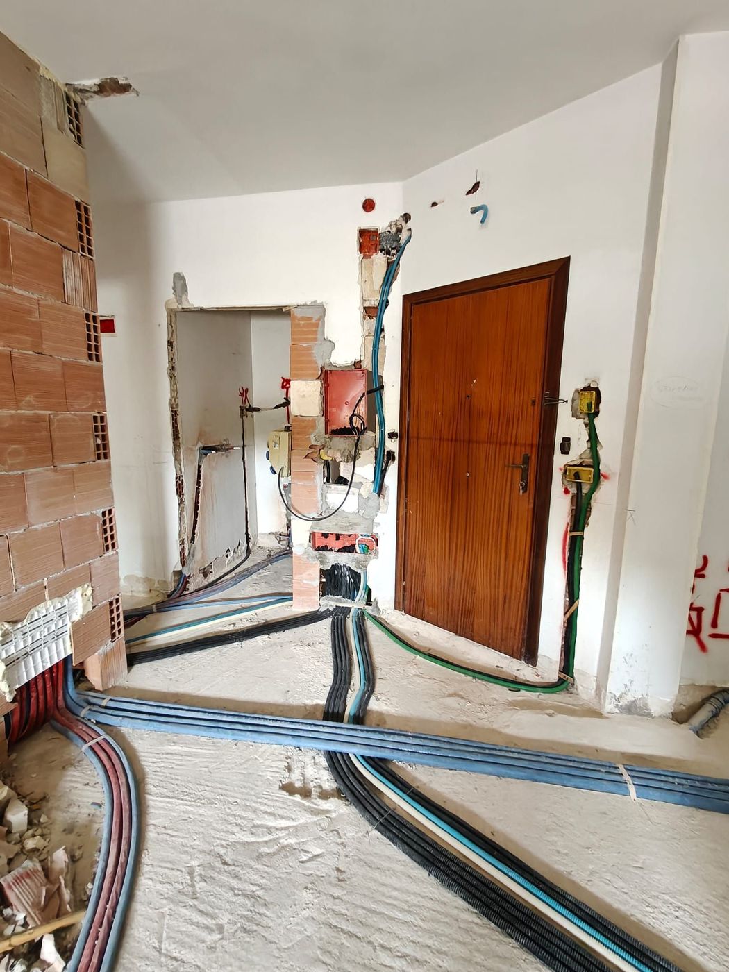 Una mano che regge uno smartphone con un'app per la sicurezza domestica davanti a una moderna casa bianca.