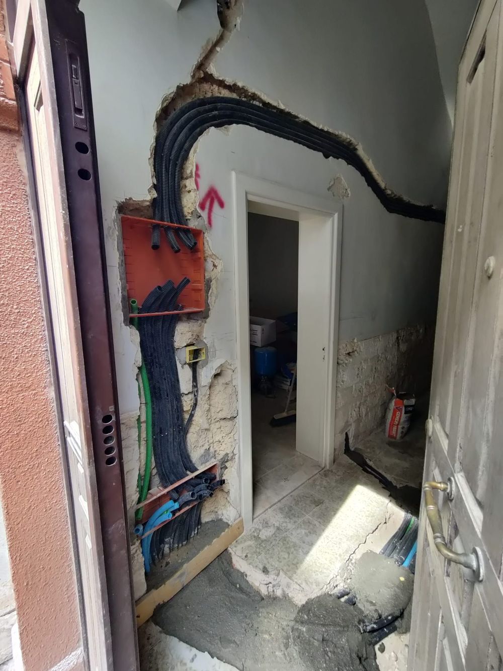 Lunga fila di pannelli di controllo elettrici grigi nel corridoio di uno stabilimento industriale.