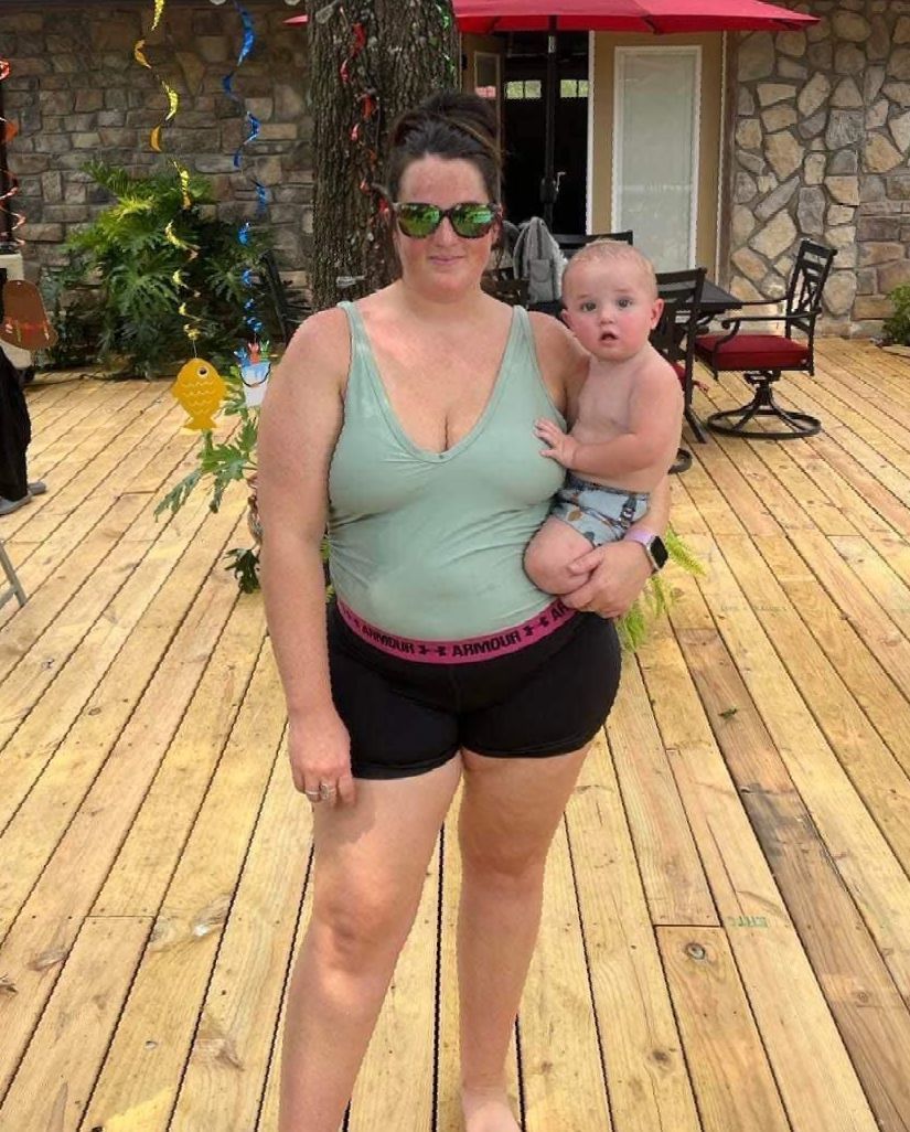 a woman is holding a baby on a wooden deck