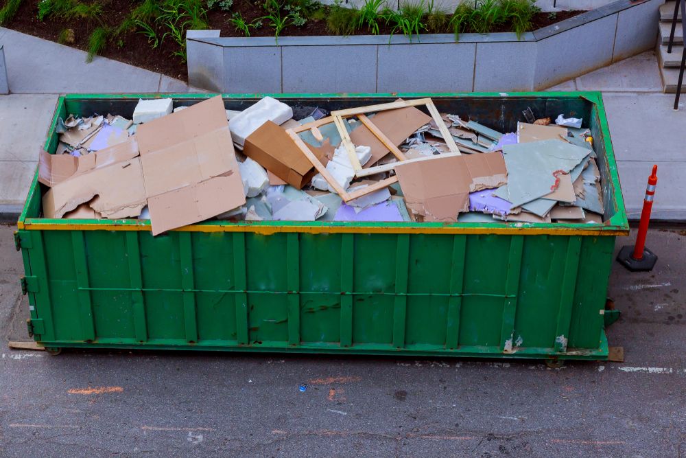 A Green Dumpster Filled With Cardboard Boxes And Other Trash On The Side Of The Road — Tamworth Skip Eze In Taminda, NSW