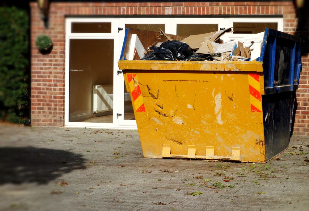 A Yellow Dumpster Is Sitting In Front Of A Brick Building — Tamworth Skip Eze In Taminda, NSW