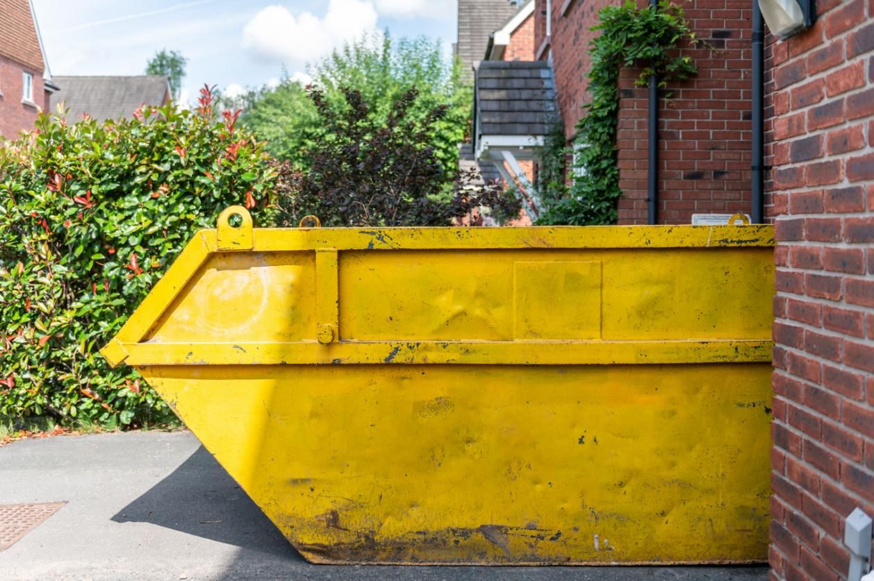 A Yellow Dumpster Is Parked In Front Of A Brick Building — Tamworth Skip Eze In Taminda, NSW
