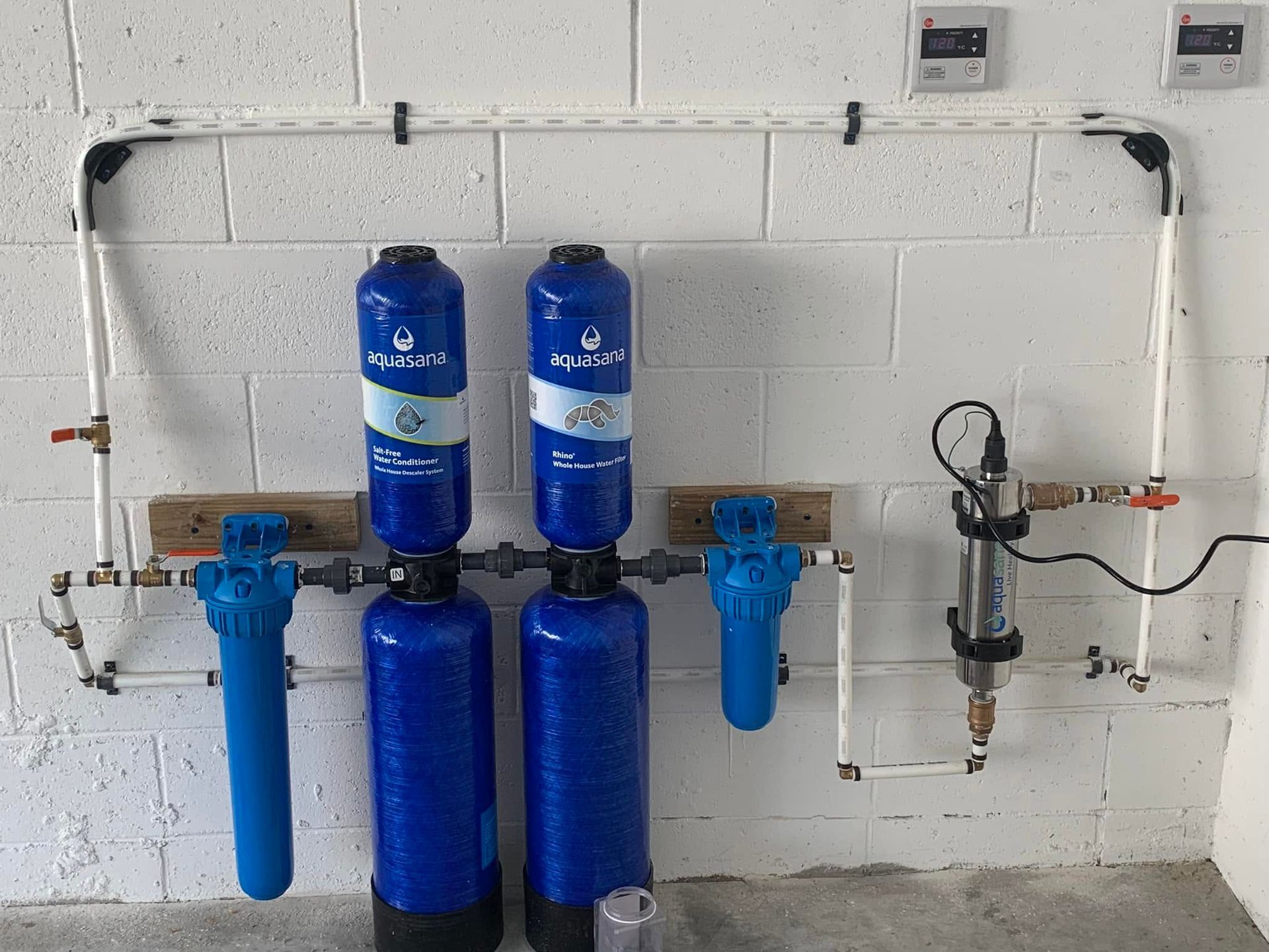 Blue water filtration system with multiple canisters and gauges mounted on a white wall