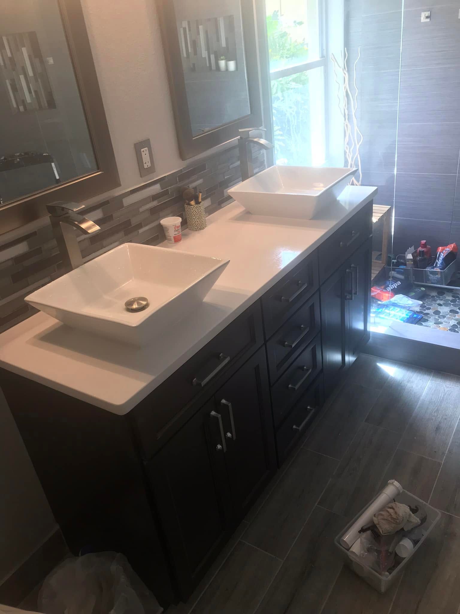 Bathroom vanity with double sinks and large mirrors, lit by daylight from a window.