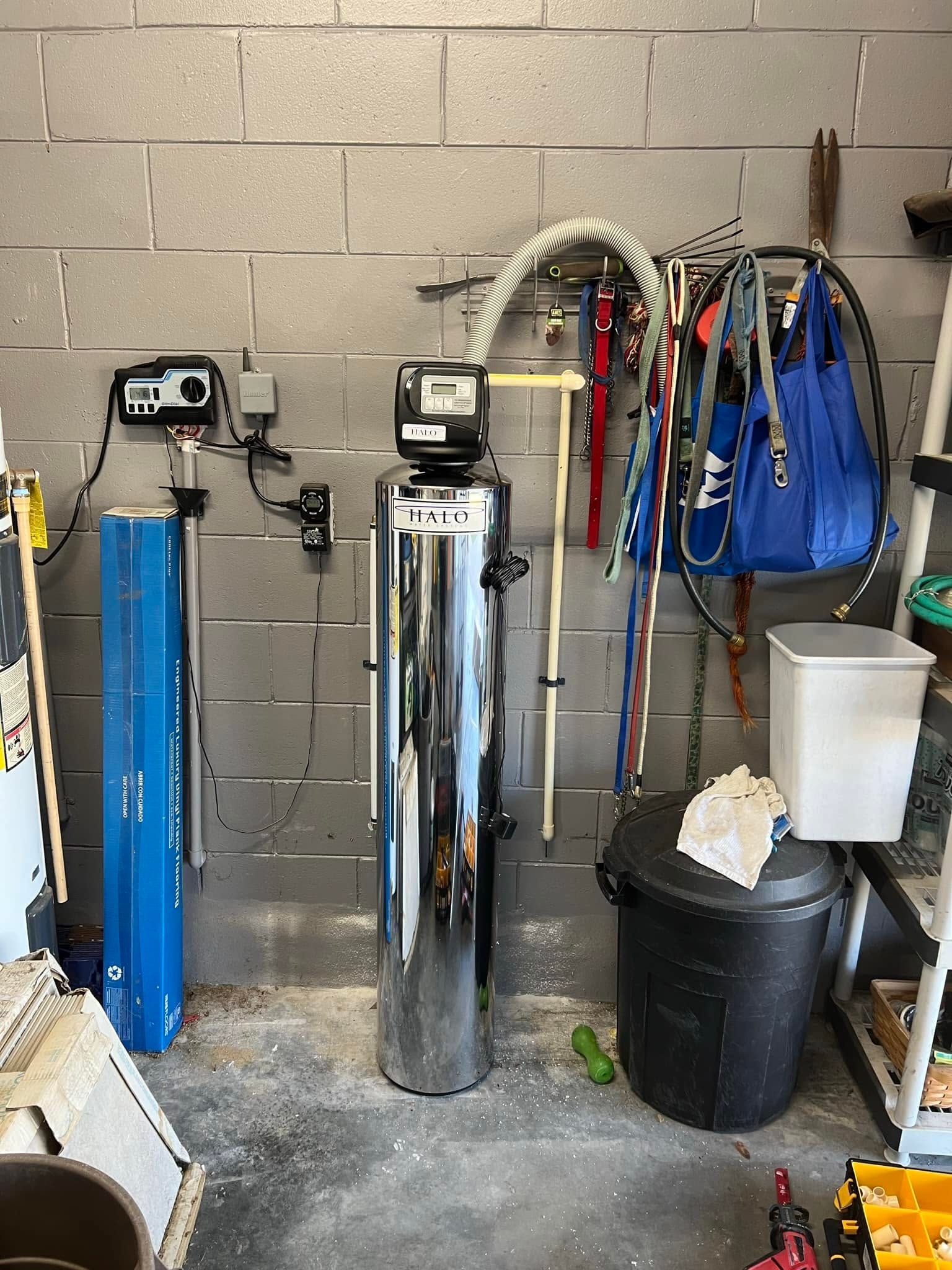 Golf club bag storage area with two golf clubs, hanging bags, and equipment against a cinderblock wall