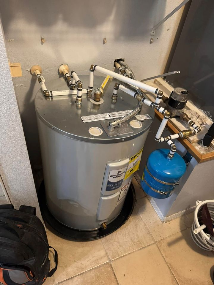 Water heater with pipes and blue expansion tank in a utility closet
