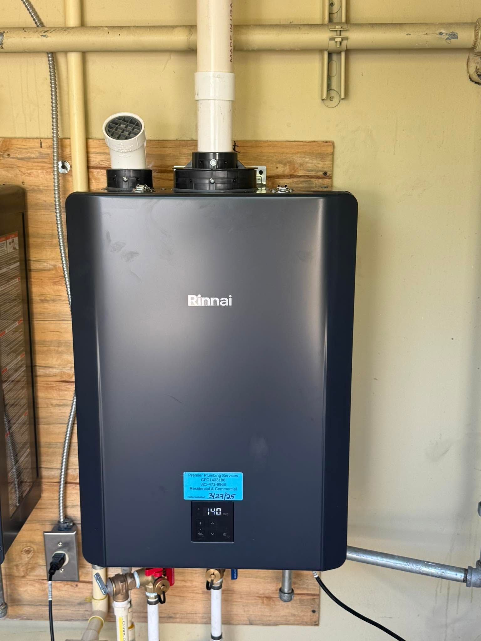 Wall-mounted black water heater with white vent pipes in a utility room