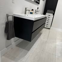 Modern bathroom with black floating vanity, white sink, wall mirror, and towel hanging on the side.