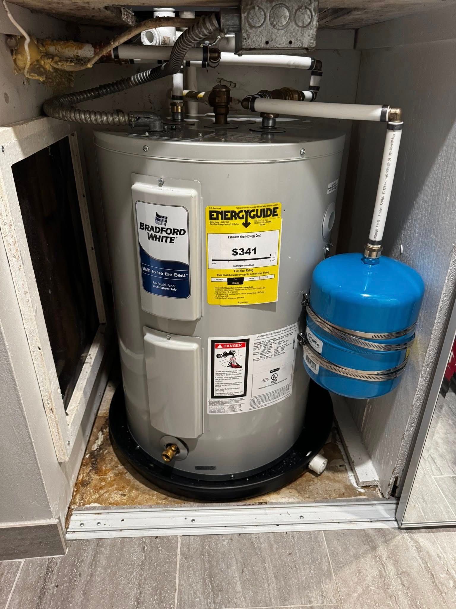 Water heater with blue expansion tank in a utility closet.