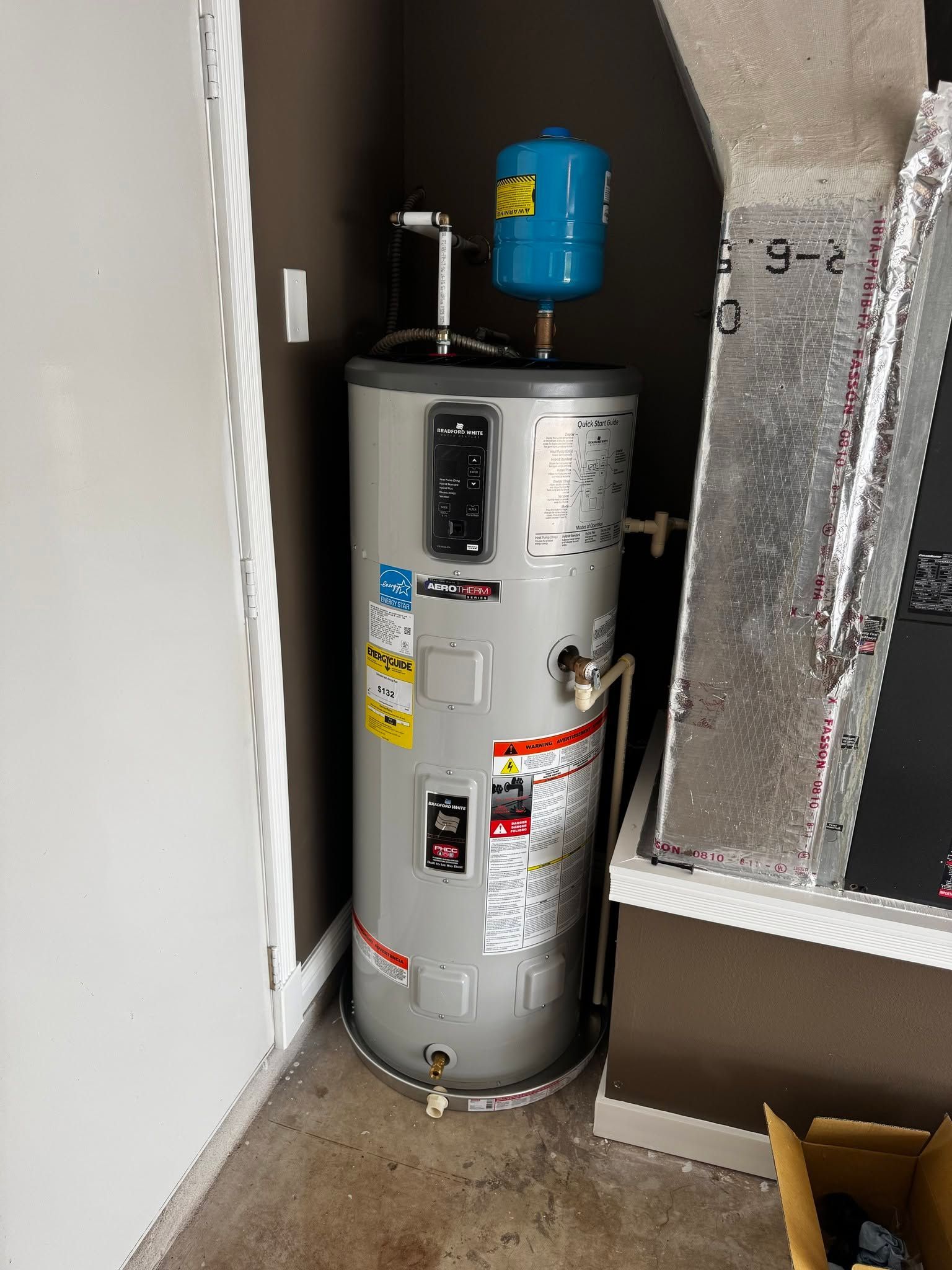 Water heater with blue expansion tank in a narrow utility closet beside ductwork and walls.