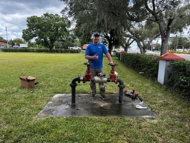 Man in blue shirt standing on an outdoor concrete water pump platform in a grassy park