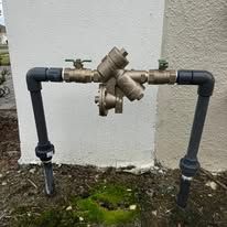 Outdoor gas pipe with shutoff valves and regulators mounted on two black vertical posts.