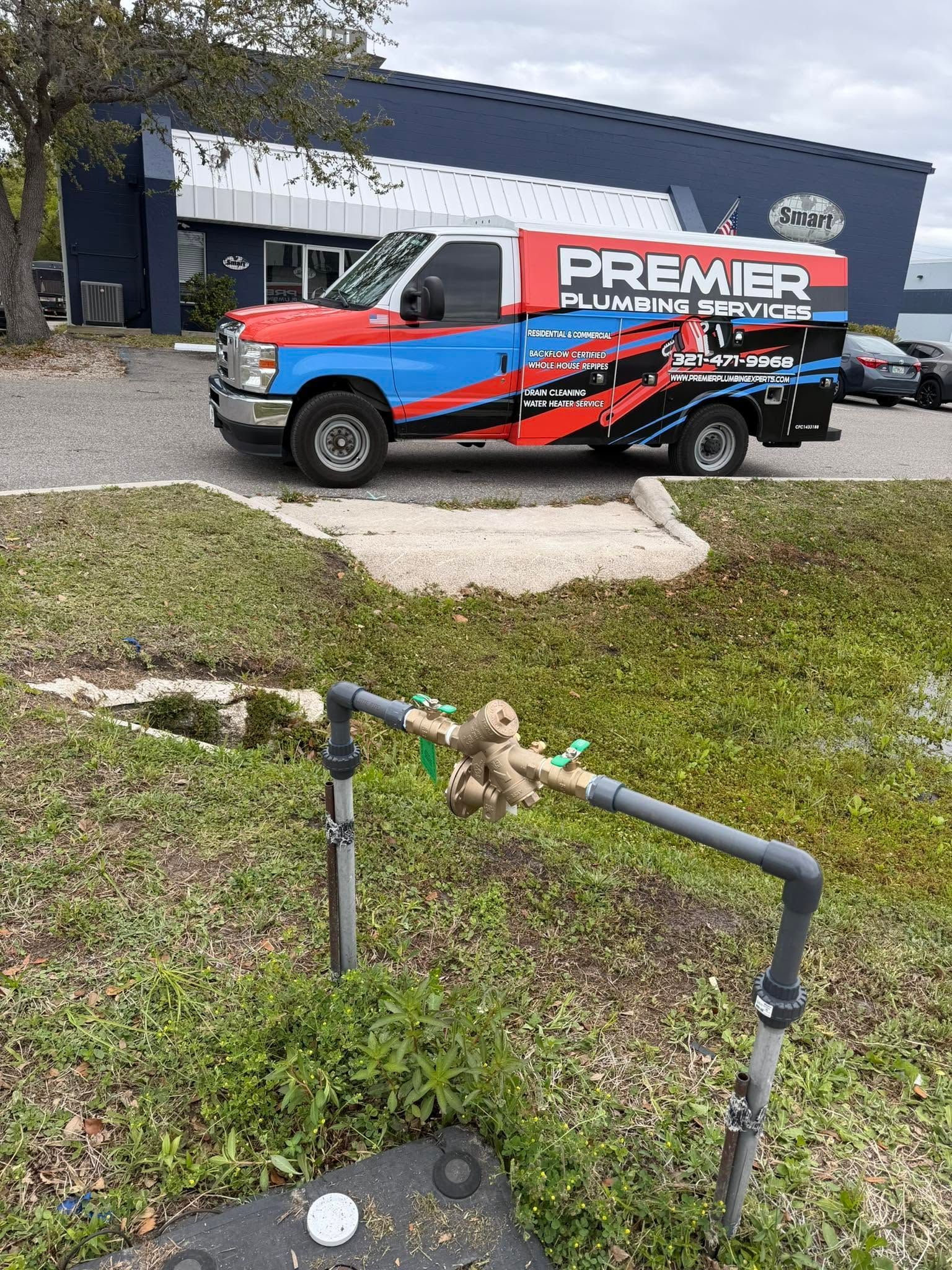 Water meter in grass foreground with a Premier-branded utility truck parked in front of a building.