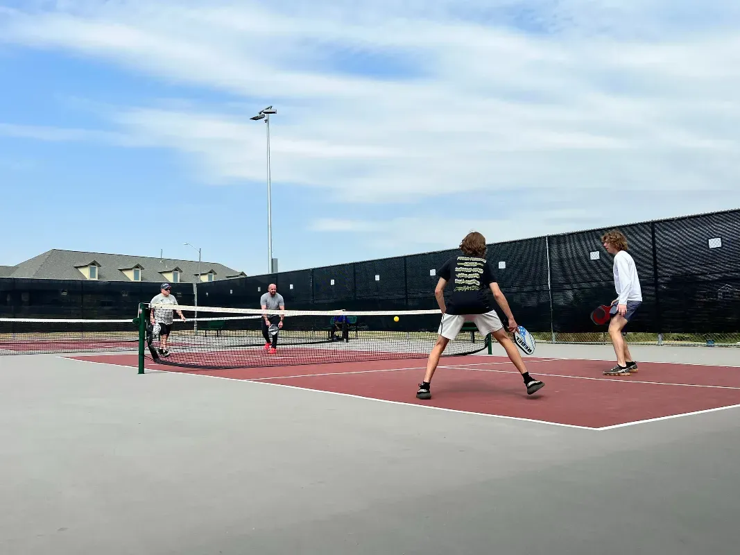A group of people are playing tennis on a court.