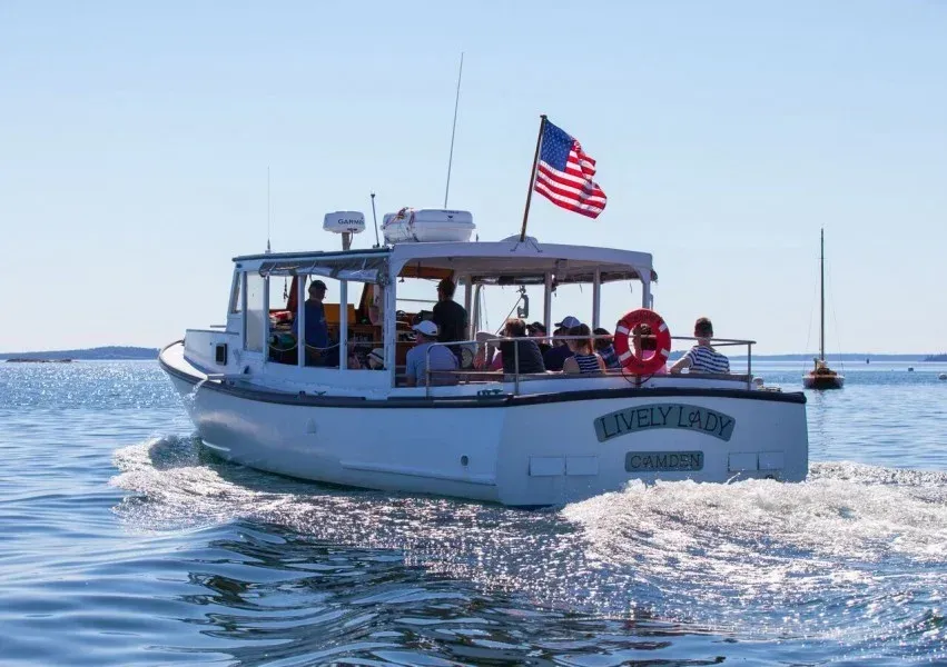A boat with people on it is floating on top of a body of water.