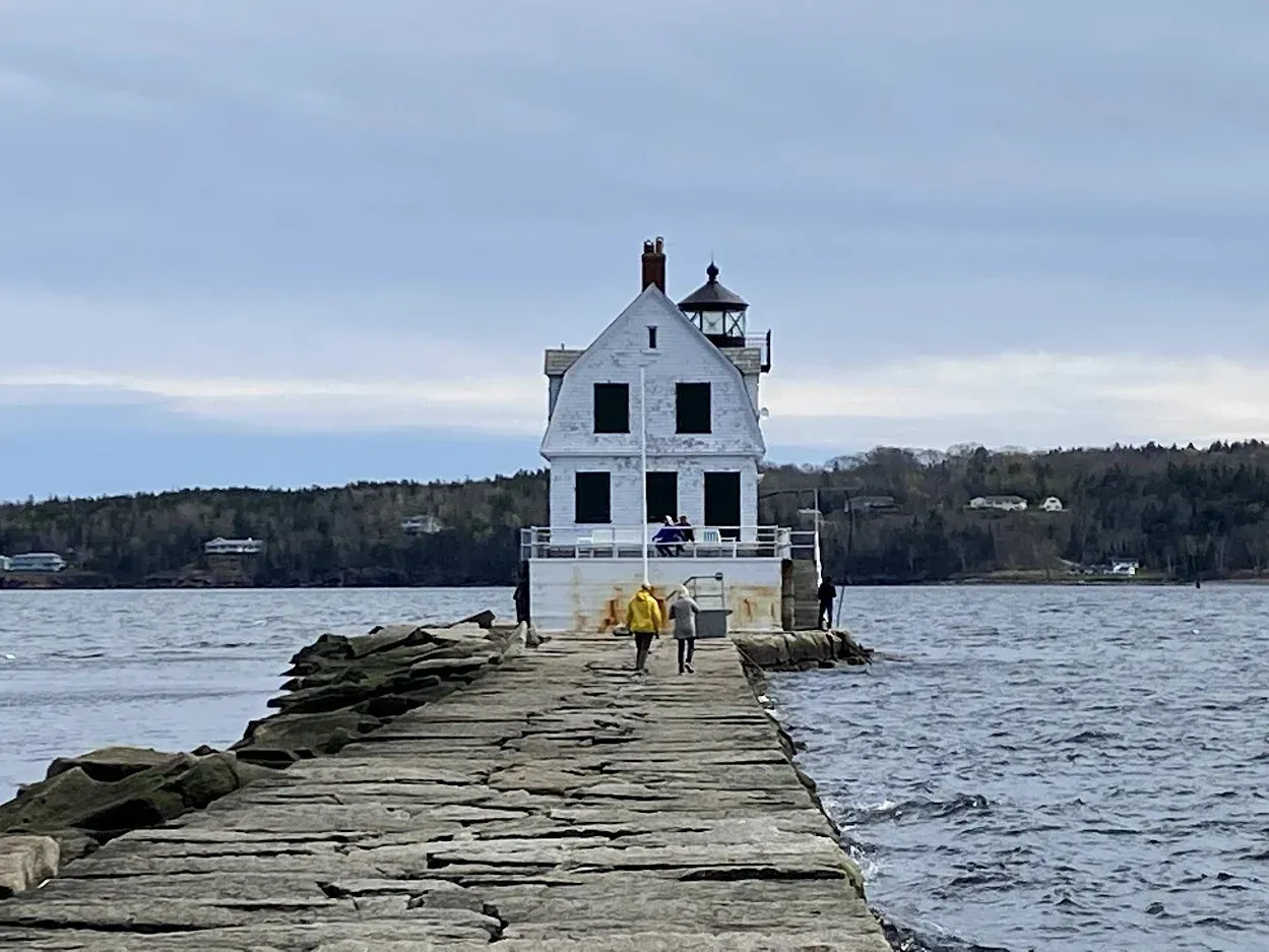 A lighthouse is sitting on the shore of a body of water.