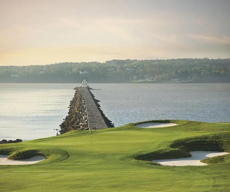 A golf course with a pier in the middle of the water.