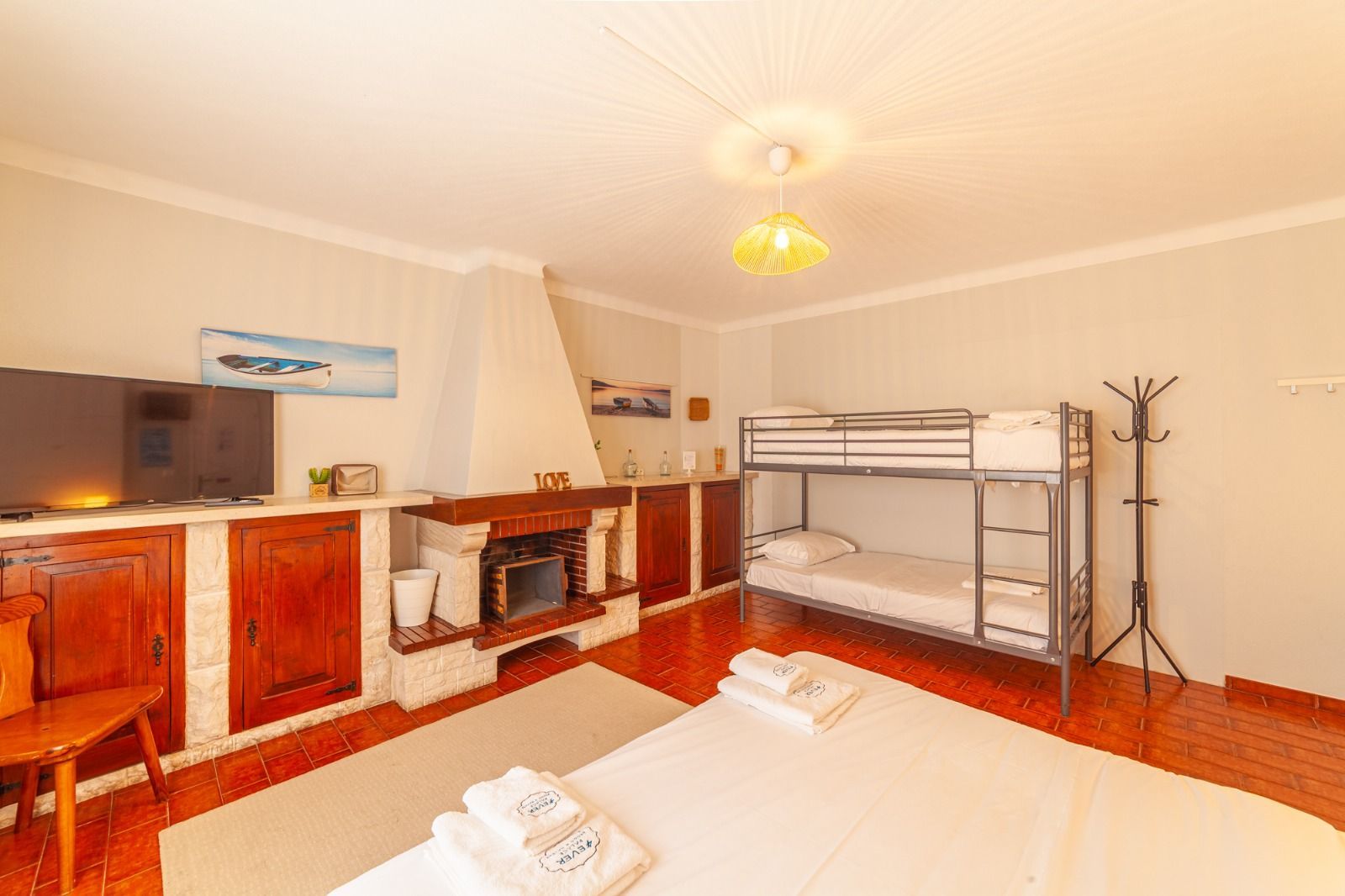 Cozy room with bunk bed, fireplace, cabinets, and a bed with folded towels in the foreground