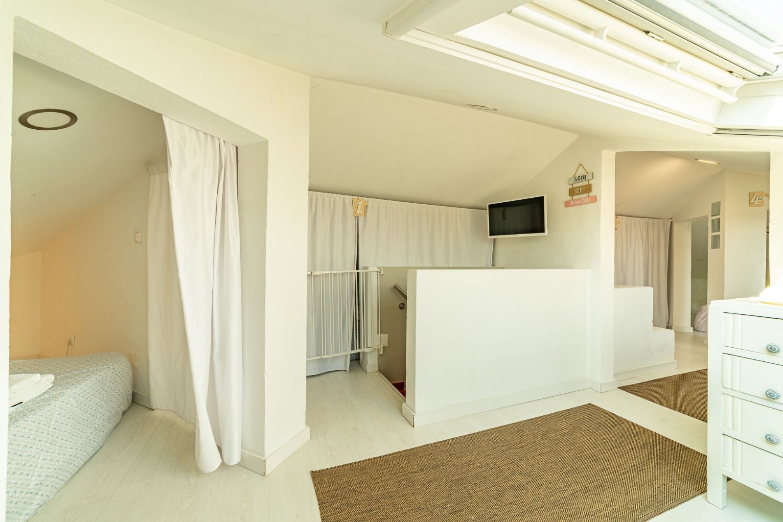 Bright modern bedroom with a curtained bed alcove, white partition, and patterned rug