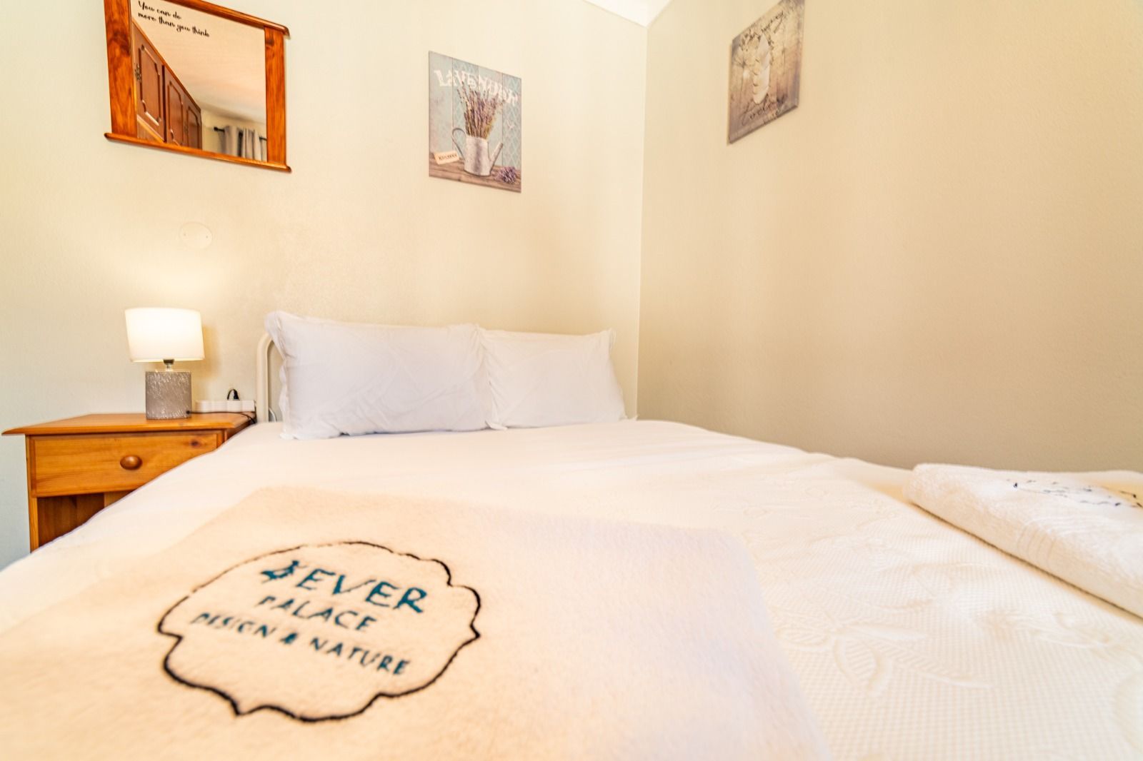 Neatly made bedroom with white bed, bedside lamp, and soft beige walls.