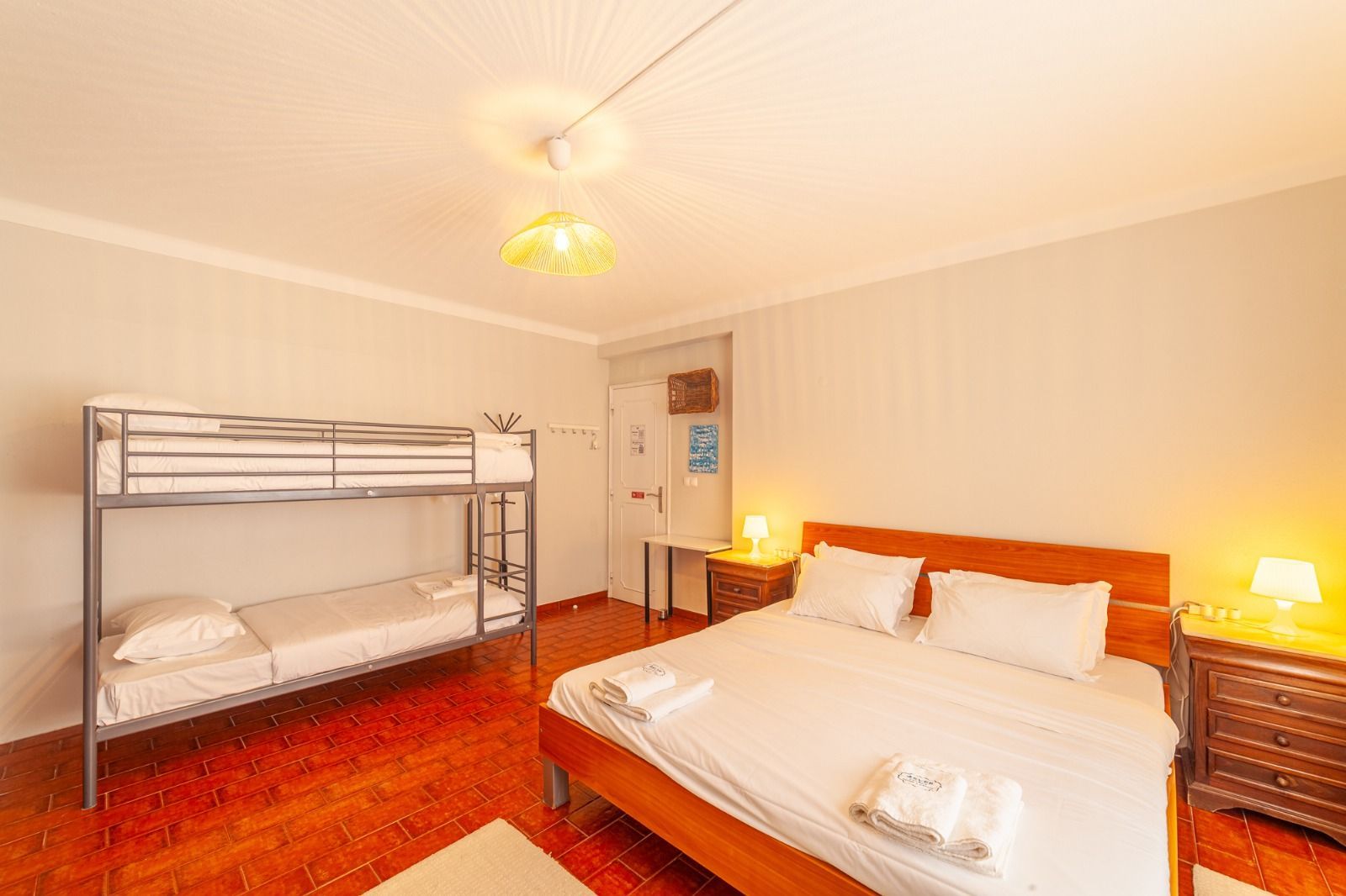 Bright bedroom with a bunk bed, double bed, bedside lamps, and orange carpet