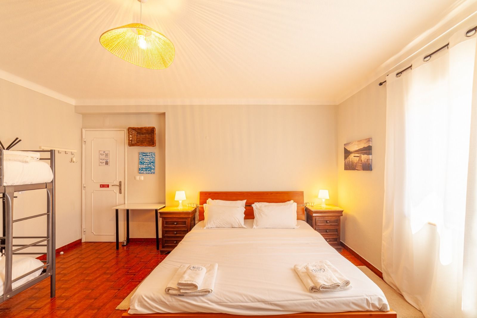 Bright bedroom with a bed, bedside lamps, wardrobe, and sunlight through large windows