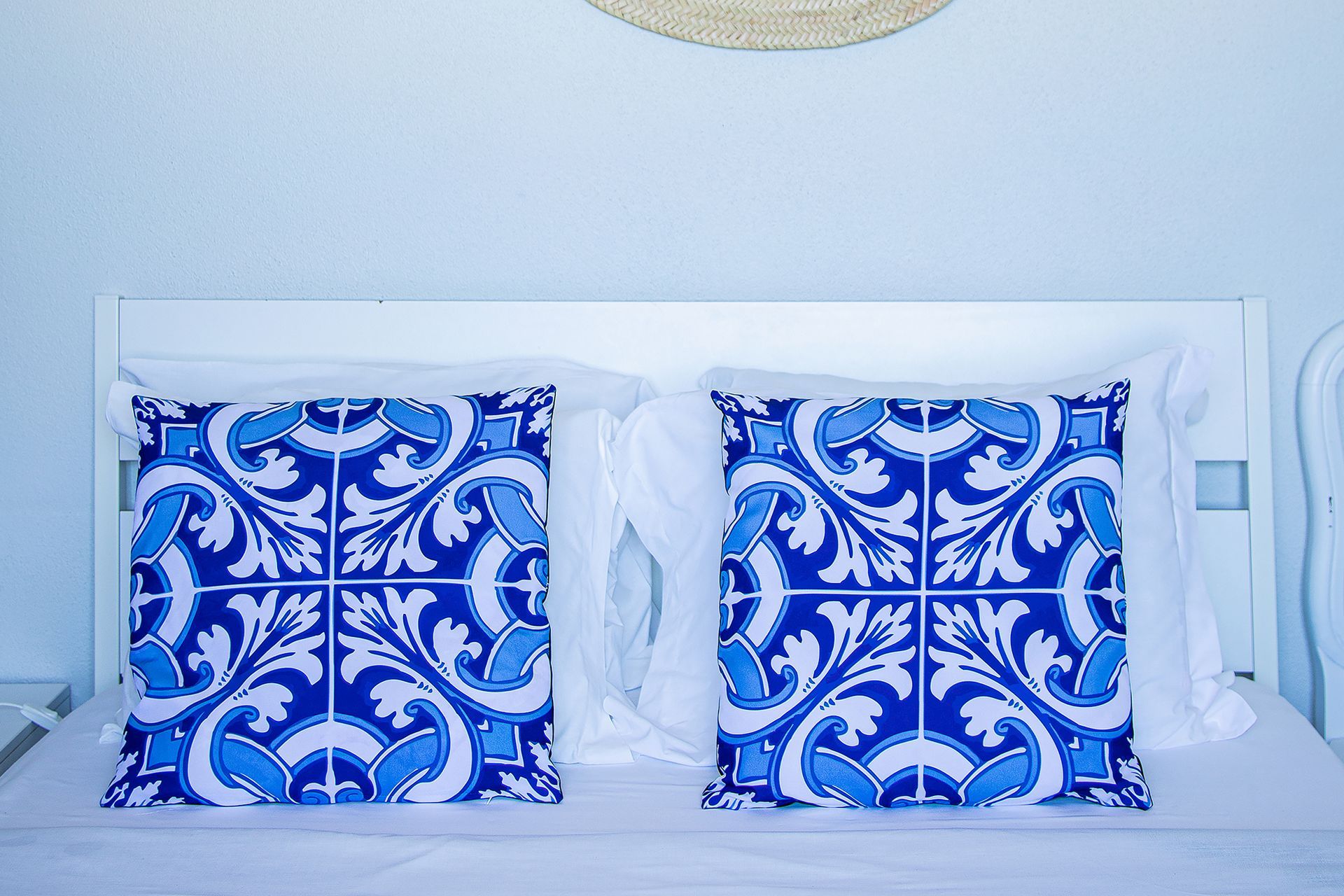 White bed with two blue patterned pillows in a bright room
