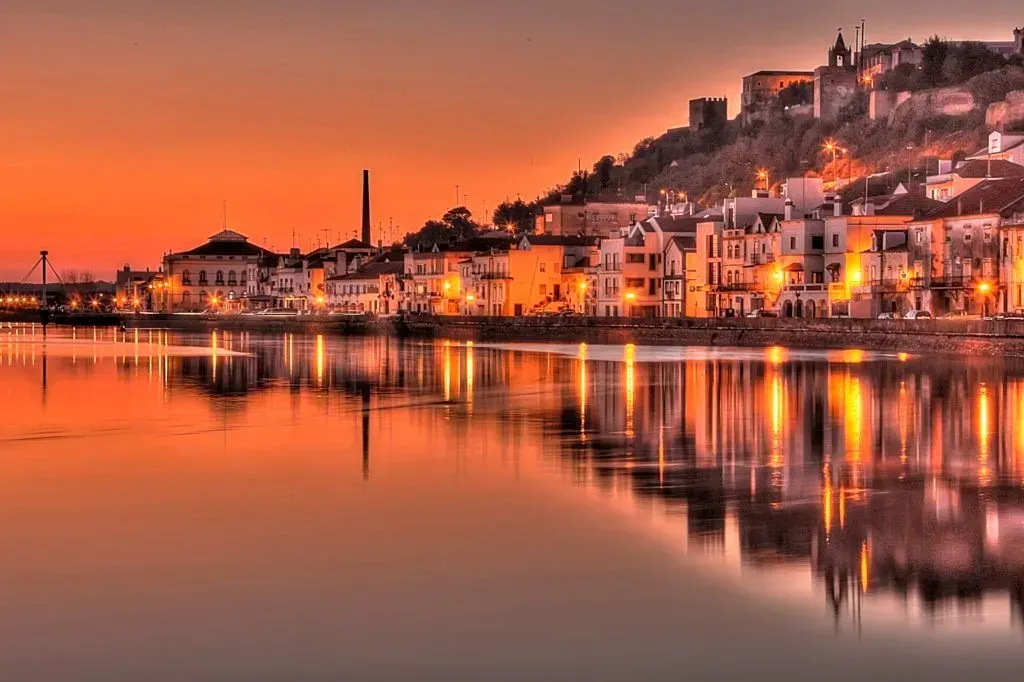 Sunset over a waterfront town with warm orange lights reflected in calm water