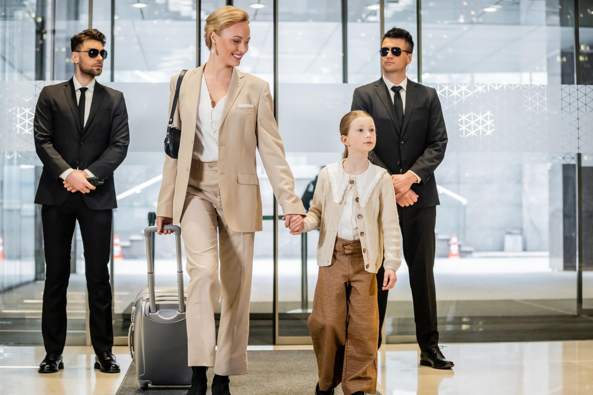 Woman and child leaving a building, accompanied by two security guards.