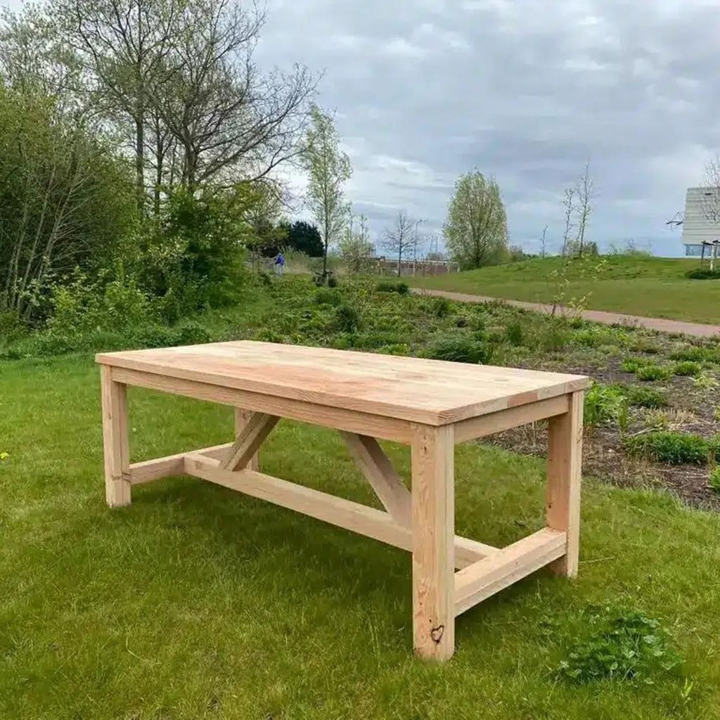 Houten picknicktafel in de buitenlucht op een grasveld onder een bewolkte hemel.