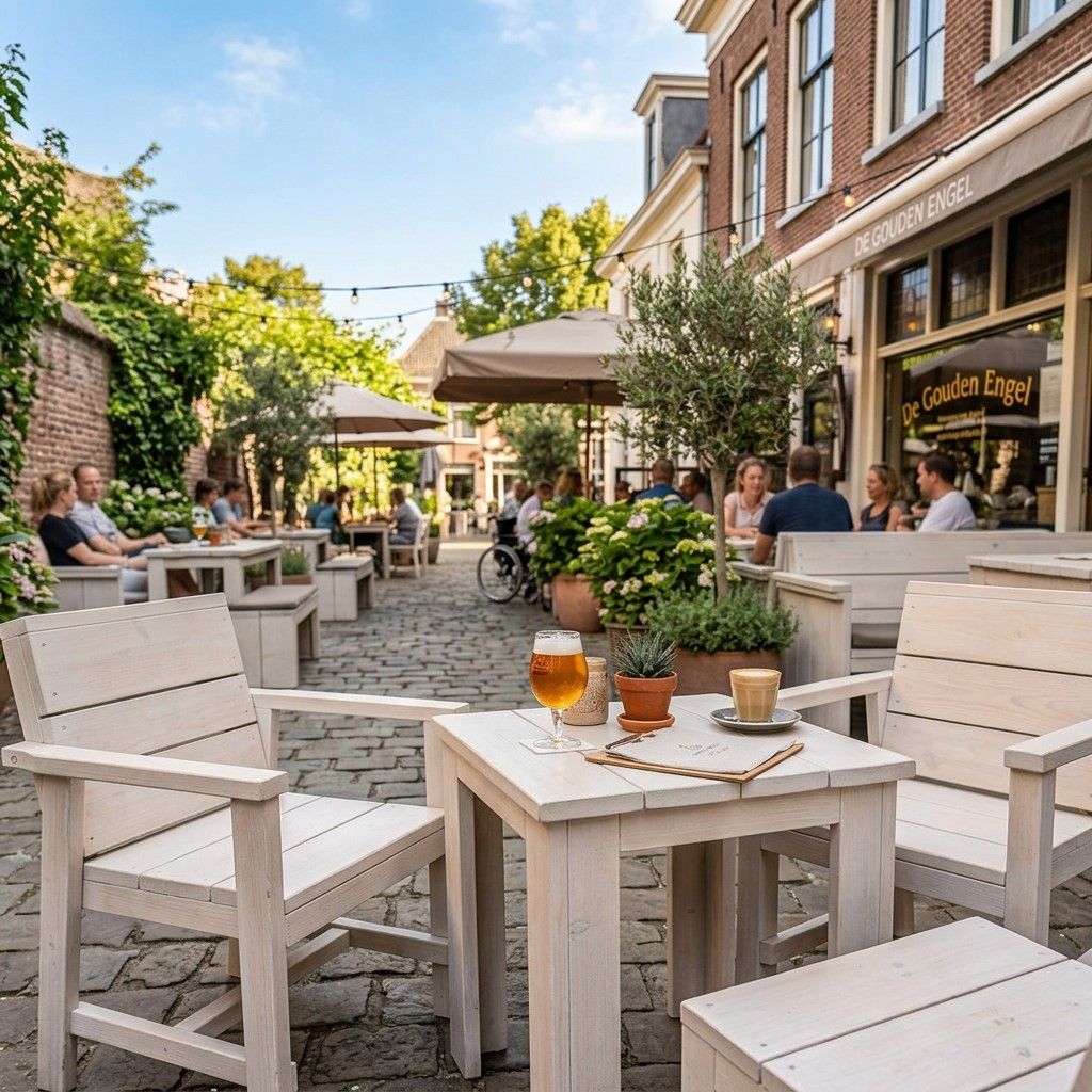 Een terras van een café in de buitenlucht met witte tafels en stoelen, potplanten en zittende gasten naast een bakstenen gebouw.